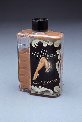 Image of a bottle of white leg paint with picture of a woman's leg on a black label