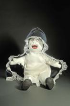 Cloth doll with painted facial features and lace bordered cloak